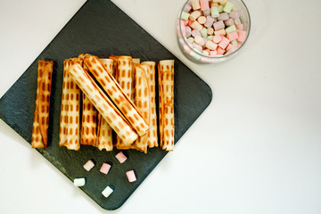 waffle tubes on black Board and marshmallow on white background