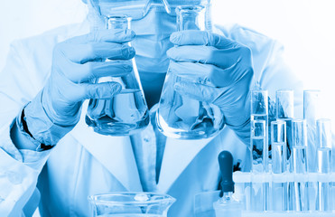 Laboratory beaker in analyst's hand in plastic glove