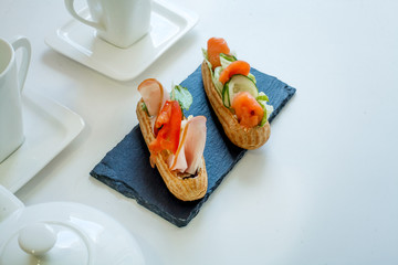 eclairs with salmon fresh vegetables and greens on a white background, gourmet snacks on a background of expensive white handmade porcelain
