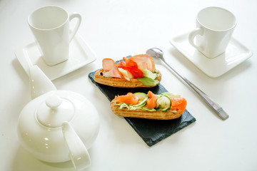 eclairs with salmon fresh vegetables and greens on a white background, gourmet snacks on a...