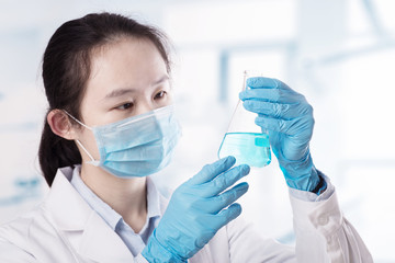 Laboratory beaker in analyst's hand in plastic glove