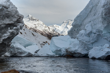 pieces of snow from the mountain avalanche in the river against the backdrop of mountain peaks, the Gonachkhir river Karachay-Cherkess Rep. Russia