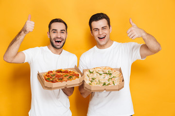 Image of two bearded men bachelors 30s in white t-shirts smiling and holding pizza boxes