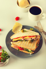 Homemade sandwich. Toasted double panini with ham, cheese fresh vegetables. Snack at work or lunch. Light background.