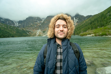 Happy young man proudly waiting for adventure in the mountains