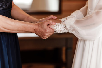 Bride on wedding day holding her mother's hands. an old woman holds her young daughter married.