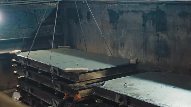 Crane move down fabricated concrete slab to the drying chamber. Production of reinforced concrete panels