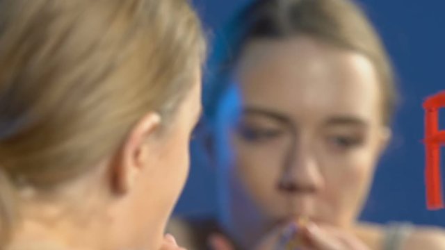 Teen girl greedily eating cake, fat word written on mirror, bulimia disorder