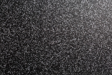 Close up of decorative quartz sand epoxy coated floor or wall coating with grey and black coloured particles. Side lighted