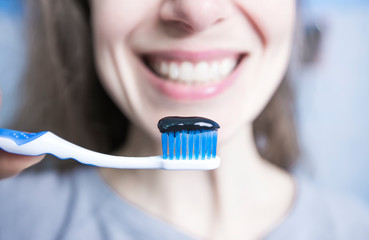 Toothpaste and brush of black activated carbon. Charcoal in the hands of a woman. 