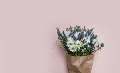 Wild flower bouquet of lavender and camomile on pink background