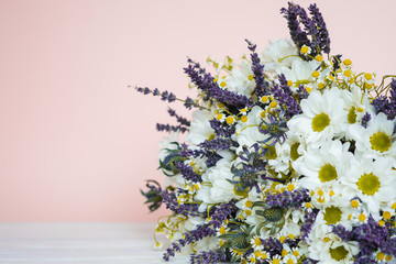 Wild flower bouquet of lavender and camomile on pink background