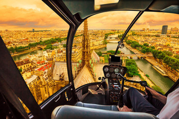 Helicopter cockpit flying at sunset on Notre Dame de Paris cathedral and on skyline of Paris, French capital, Europe. Scenic flight over Paris cityscape.