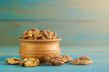 Fototapeta na wymiar Walnuts on blue rustic table in wooden bowl