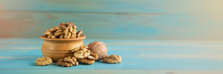Walnuts on blue rustic table in wooden bowl