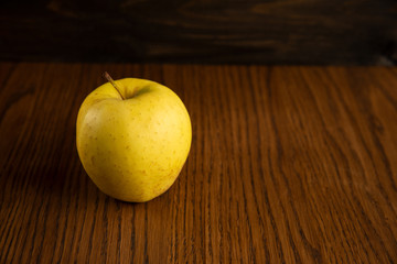 Yellow apple on the wooden vintage background