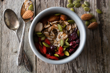 Healthy breakfast.Two bowls of muesli with oats, nuts and dried fruits - apples, resins, pumpkin seeds and almonds on wooden table. Top view. Rustic style.