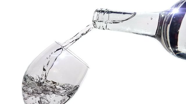 Pouring clean water from the bottle into the glass. Slow motion footage with water flow on white background.