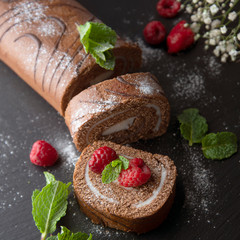 Delicious chocolate roll sponge cake with vanilla cream and mint leaves. Desert sweet food.