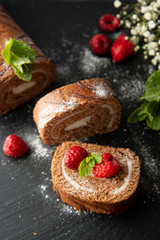 Delicious chocolate roll sponge cake with vanilla cream and mint leaves. Desert sweet food.
