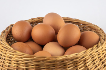 wicker basket with dietary brown eggs, front view, on a wooden table