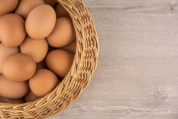 wicker basket with dietary brown eggs, top view, on a wooden table