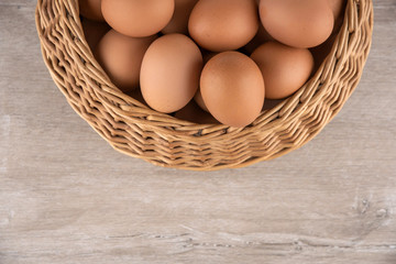 wicker basket with dietary brown eggs, top view, on a wooden table