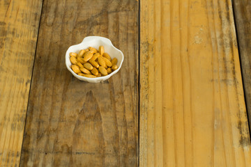 Drugs in the form of capsules, tablets and gelatin in oyster-shaped bowls on dirty wooden background