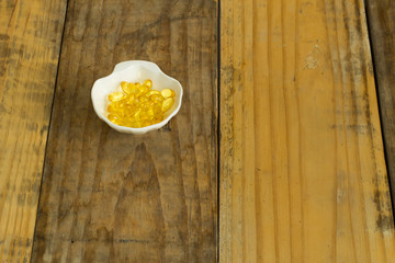 Drugs in the form of capsules, tablets and gelatin in oyster-shaped bowls on dirty wooden background