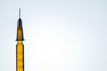 syringe with a narcotic solution inside against a background of bright light