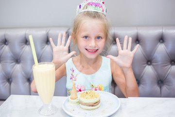 The girl at a birthday party. Joyful cheerful girl celebrates. Cocktail and cake on the table.