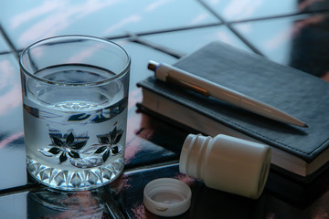 suicide: a glass with water against a background of empty blisters and a notebook, toning