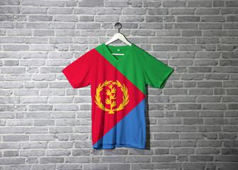 Eritrea flag on shirt and hanging on the wall with brick pattern wallpaper.