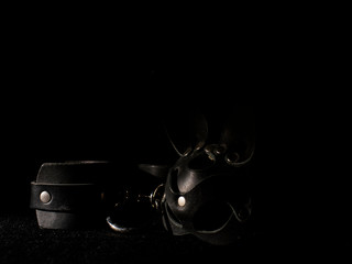 leather handcuffs and a bunny mask on a black background. fetish toys