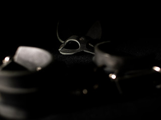 leather handcuffs and a bunny mask on a black background. fetish toys