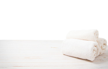 Rolled white towels on white wooden table isolated on white background. Copy space and top view. Bathroom objects for shower body treatment. Selective focus. Banner