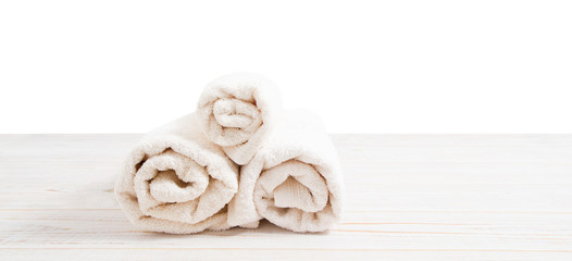 Rolled white towels on white wooden table isolated on white background. Copy space and top view. Bathroom objects for shower body treatment. Selective focus. Banner