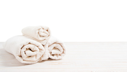 Rolled white towels on white wooden table isolated on white background. Copy space and top view. Bathroom objects for shower body treatment. Selective focus. Banner