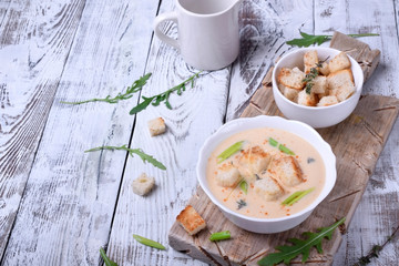 Cream soup with croutons, green onion and cheese in a white bowl