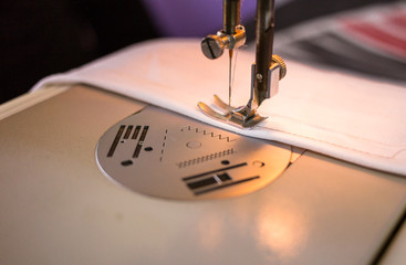 Close-up photo of sewing machine making stitch on white piece of fabric. Prom dress preparation. Fashion design concept