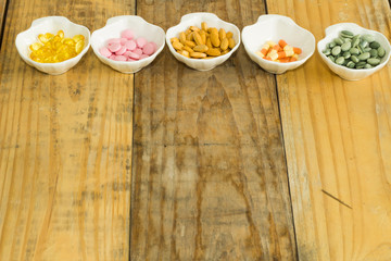 Drugs in the form of capsules, tablets and gelatin in oyster-shaped bowls on dirty wooden background