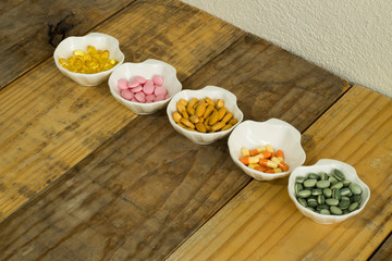 Drugs in the form of capsules, tablets and gelatin in oyster-shaped bowls on dirty wooden background