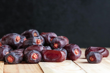 dried dates fruit  scattered on wooden table on black background copy space