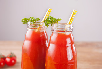 Tomato juice in bottles with parsley and salt on the wooden table