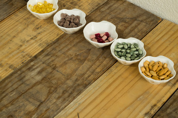Drugs in the form of capsules, tablets and gelatin in oyster-shaped bowls on dirty wooden background