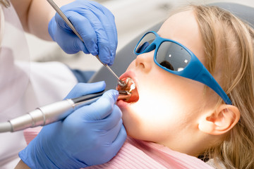 Little girl receiving dental filling procedure in pediatric dental clinic
