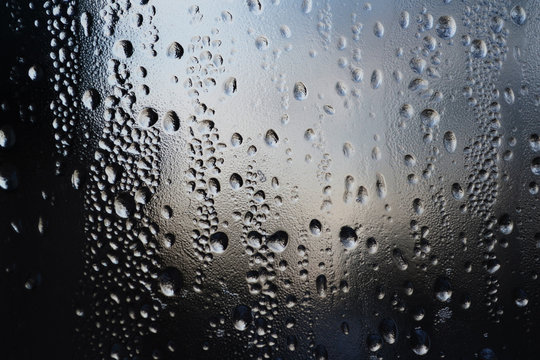 Rain drops on window glasses surface with cloudy background . Natural Pattern of raindrops cloudy background.