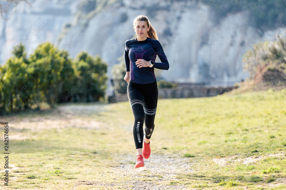 Wall mural Sporty young woman running on mountain in beautiful nature.