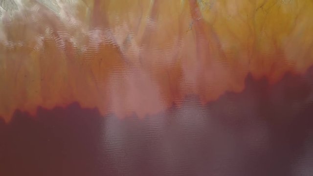 Flying above toxic waste lake with sludge at a mining exploitation. Abstract layers of colored polluted water