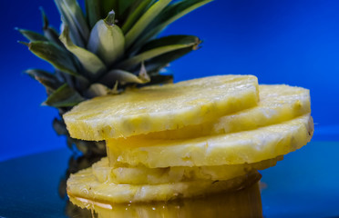 Slices of the fresh and cut pineapple on blue and bright background. Tropical, citrus fruit. A natural product for health. Exotic.